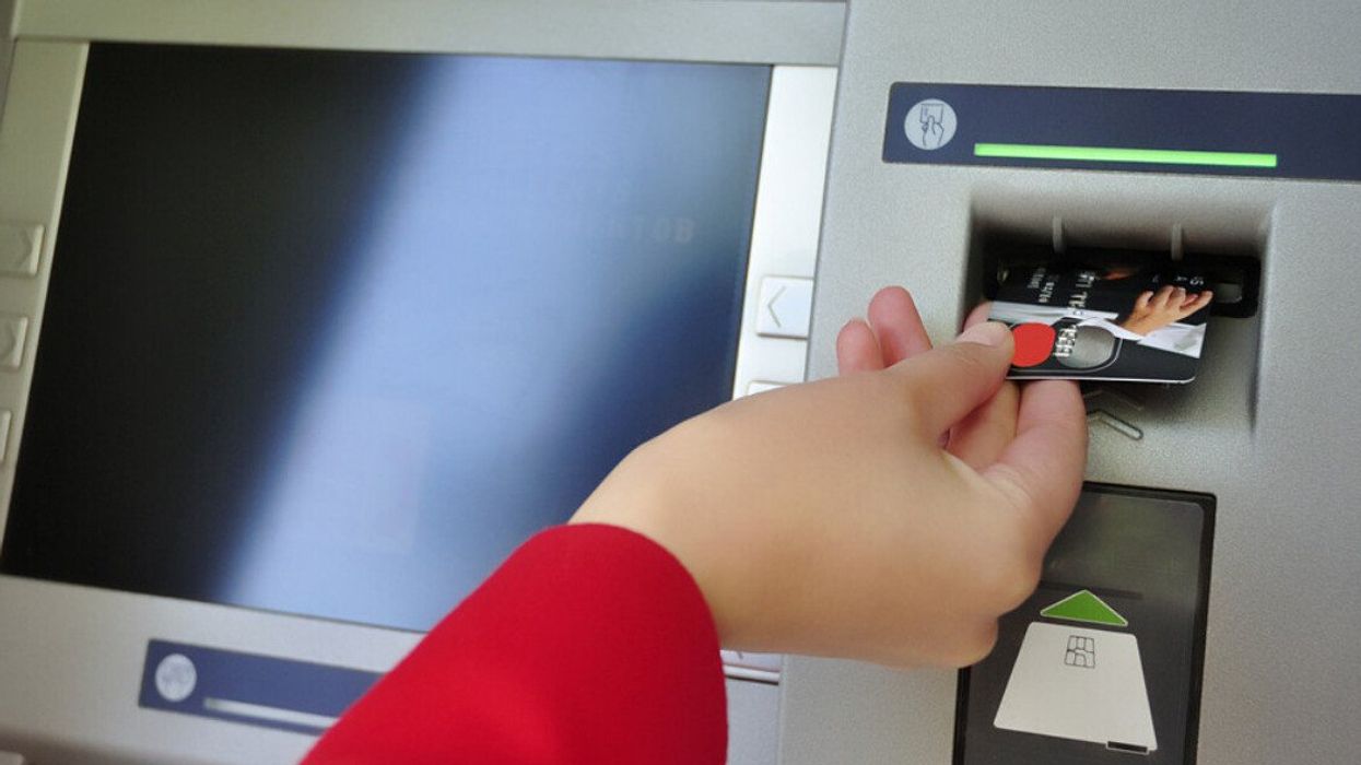 Une main insère une carte bancaire dans un guichet informatique.