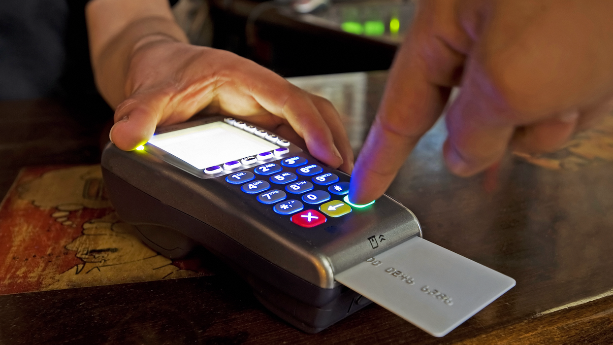Une main qui appuie sur les touches d'un terminal de paiement.