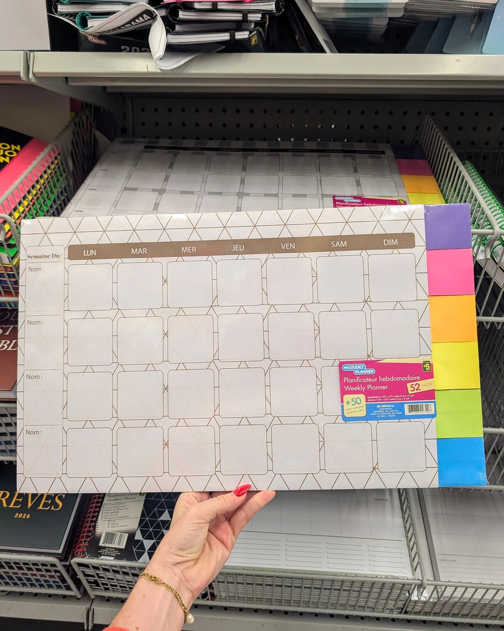 Une main qui tient un planificateur hebdomadaire vendu dans la rang\u00e9e des fournitures scolaires chez Dollarama.