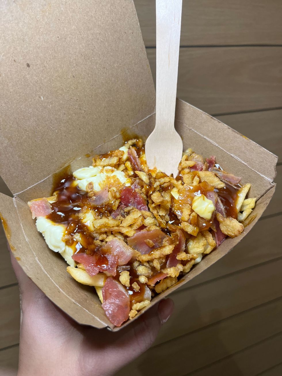 Une main tenant la Poutine P.K. du menu Face-\u00e0-Face du McDonald's
