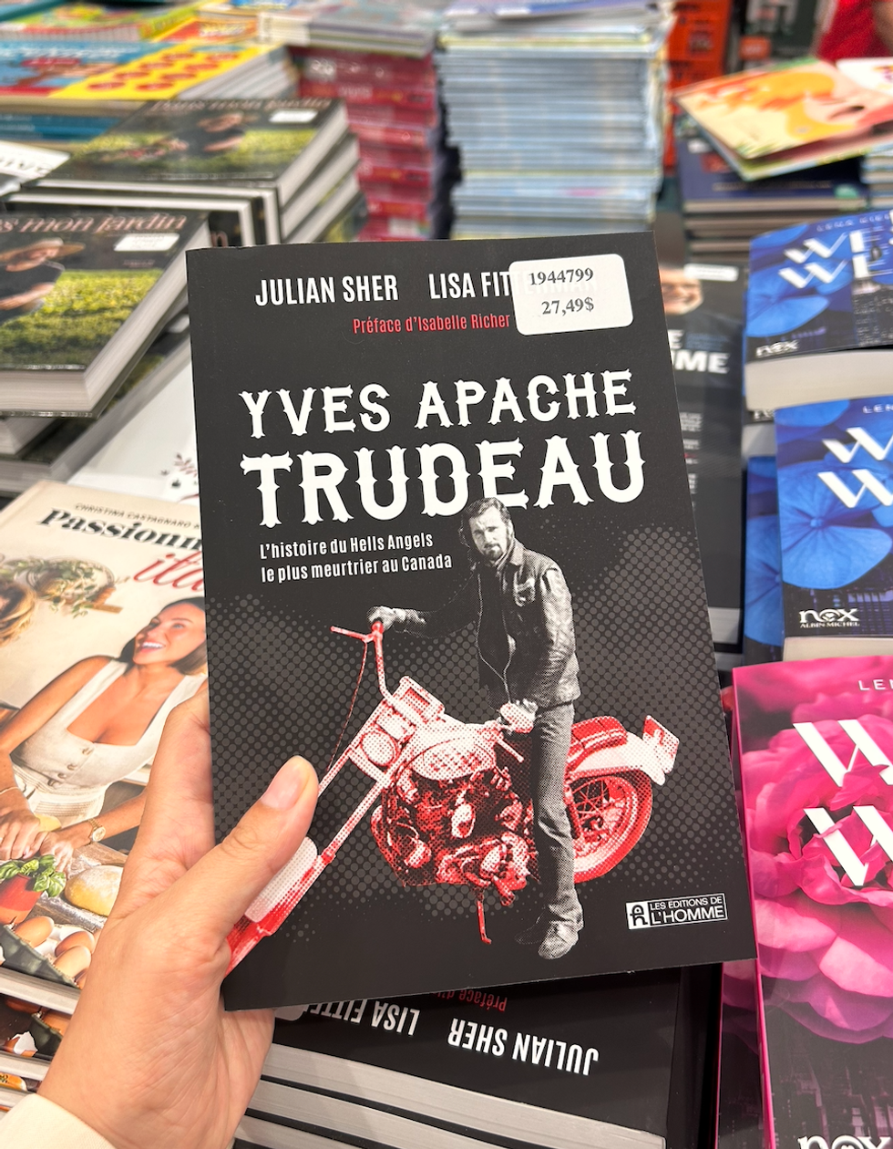 Une main tenant le livre \u00ab Yves Apache Trudeau - L'histoire du Hells Angels le plus meurtrier au Canada \u00bb au Costco.