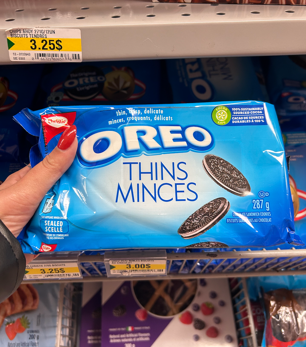 Une main tenant le paquet bleu d'Oreo minces au Dollarama.