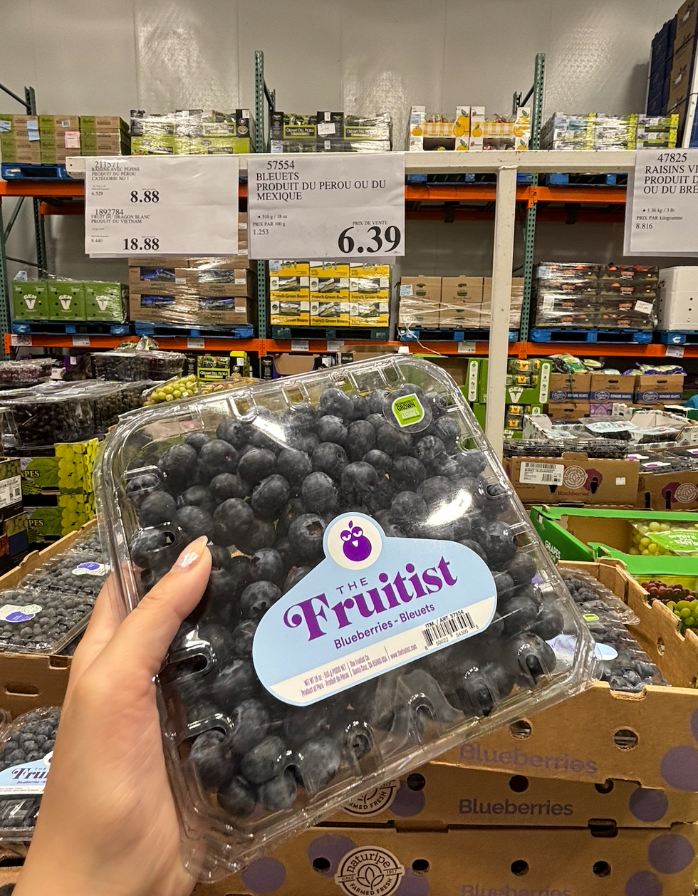 Une main tenant un casseau de bleuets The Fruitist au Costco.