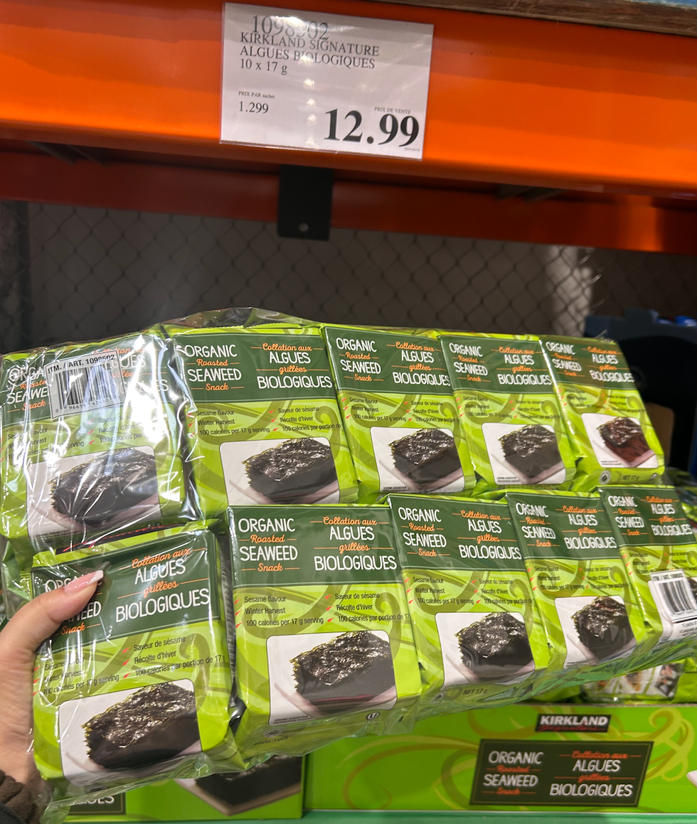 Une main tenant un paquet d'algues biologiques devant un \u00e9talage du Costco.