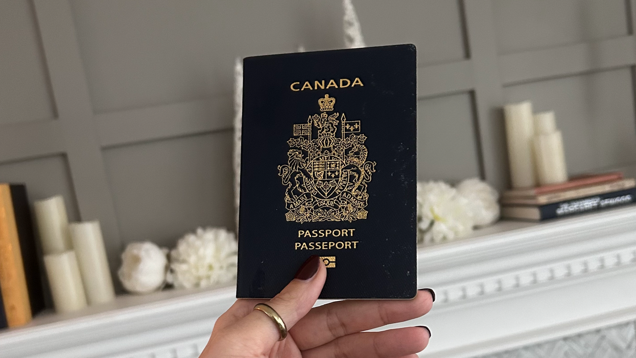Une main tenant un passeport canadien.