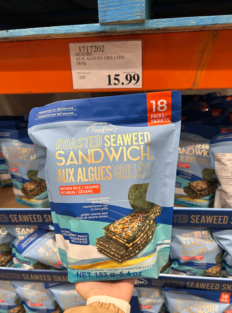 Une main tenant un sac de sandwichs aux algues grill\u00e9es Seafire devant l'\u00e9talage chez Costco.