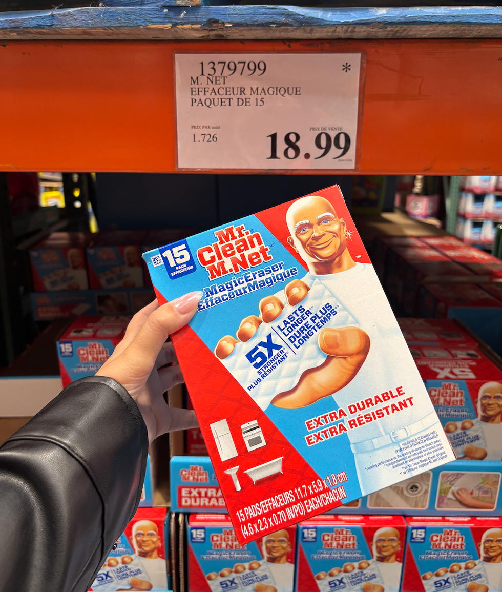 Une main tenant une boite d'effaceurs magiques de M. Net dans un rayon du Costco.