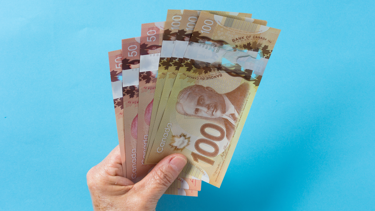 Une main tient des billets de 100 $ et de 50 $ placés en éventail.