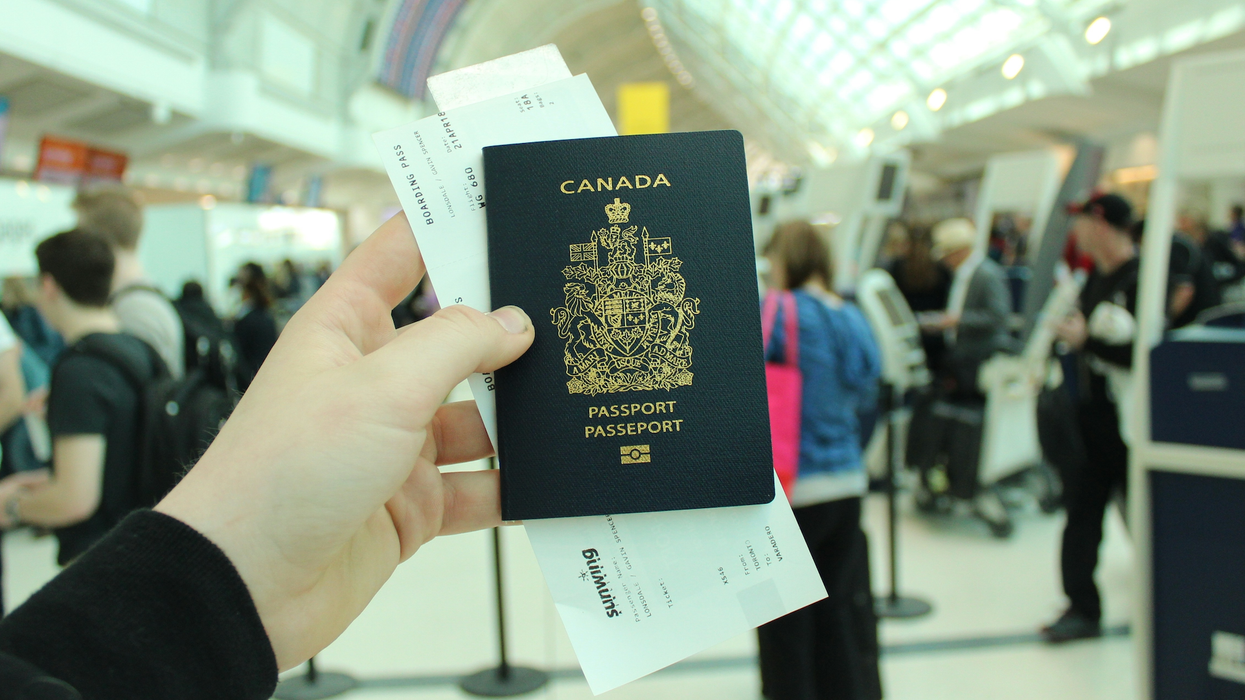 Une main tient un passeport canadien avec un billet d'embarquement à l'intérieur.
