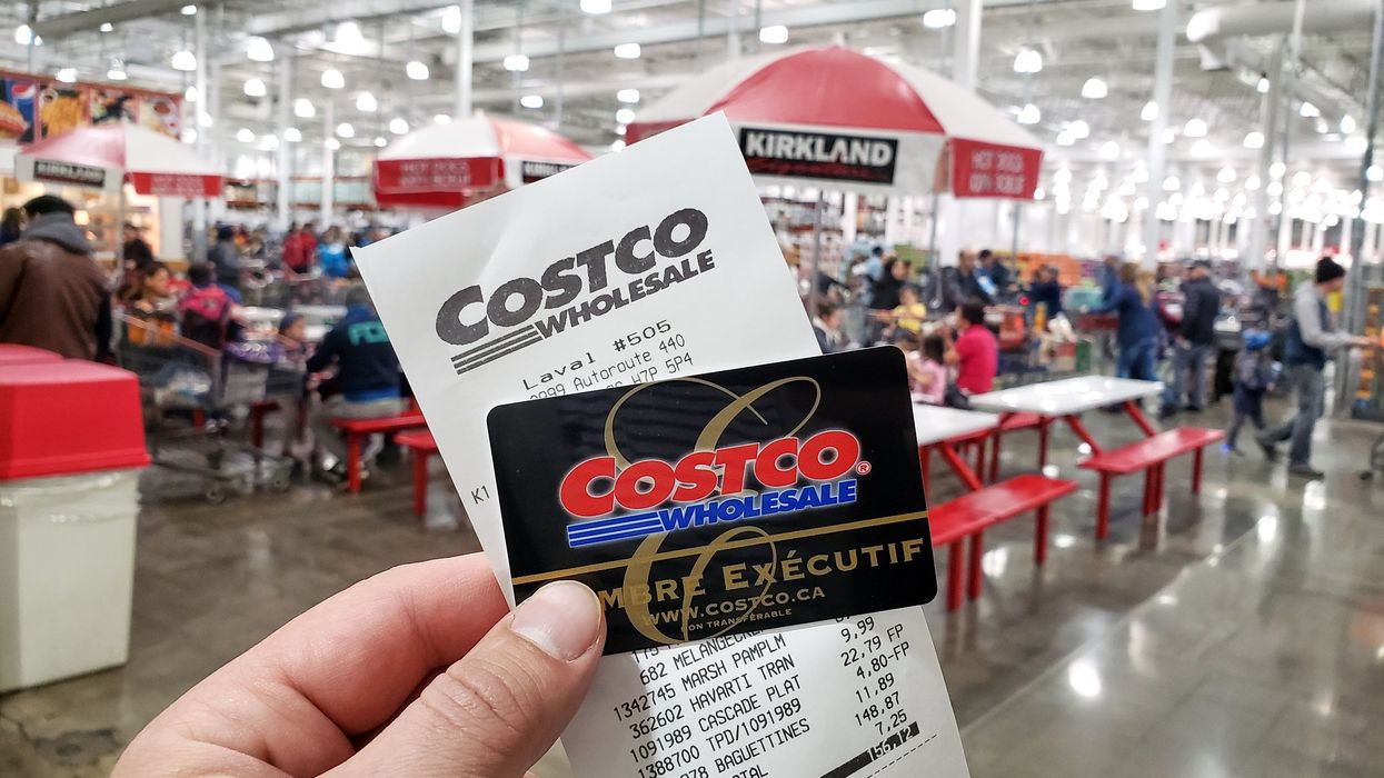 Une main tient une carte Costco et une facture.