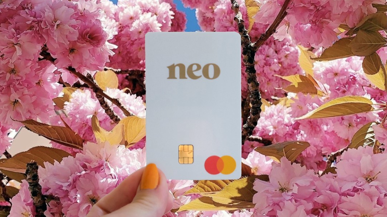 une main tient une carte de crédit devant des fleurs roses