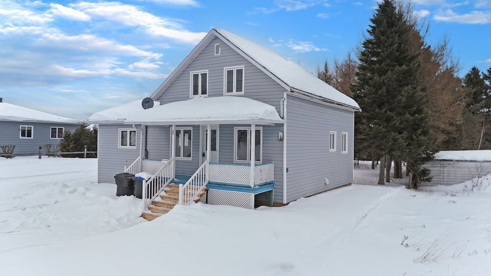 Une maison bleue sous une bord\u00e9e de neige \u00e0 vendre au Qu\u00e9bec.