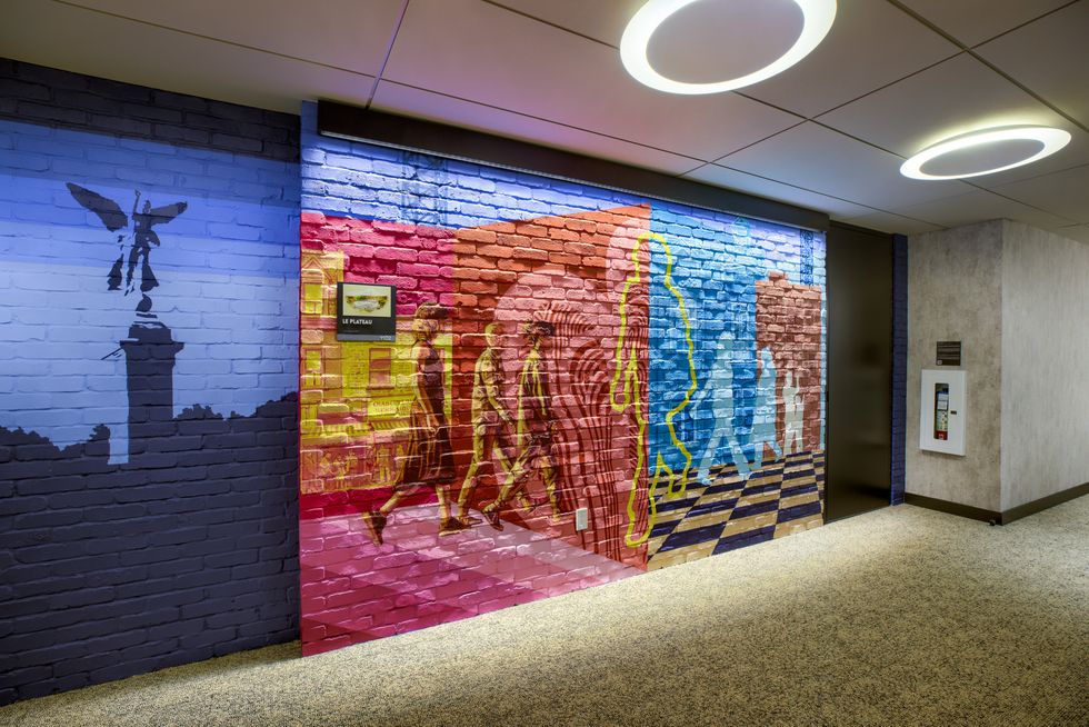 Une oeuvre d'art color\u00e9e est peinte sur un mur de briques dans un couloir de bureaux.