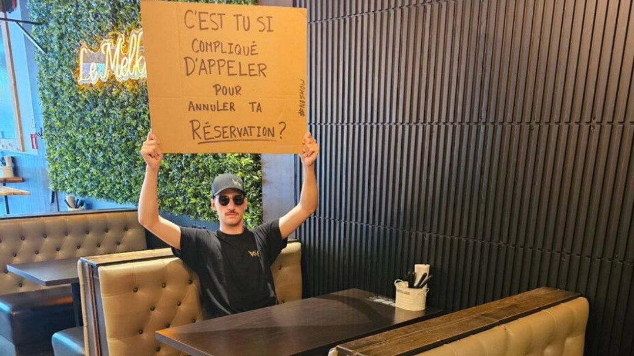 Une personne assise dans une banquette tient une affiche entre ses mains.