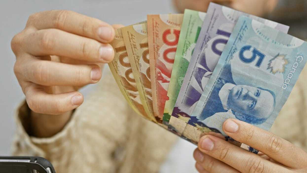 Une personne avec des billets d'argent canadien dans les mains.