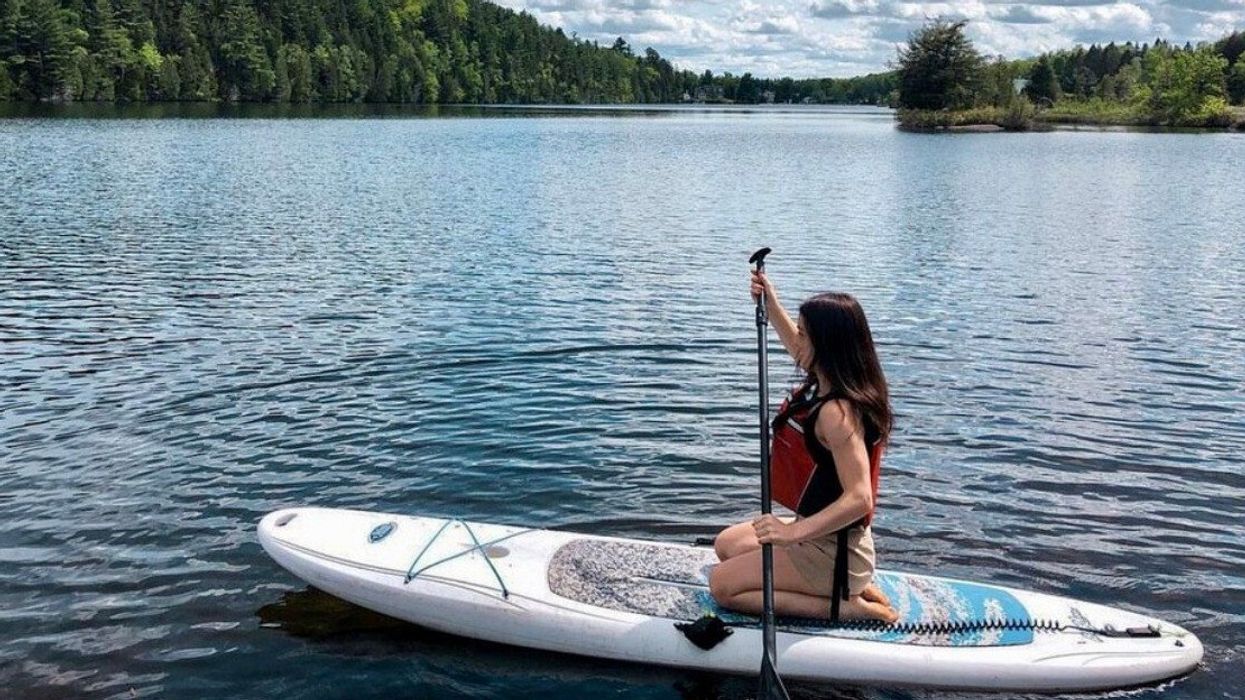 Une personne est à genoux sur une planche à pagaie sur l'eau.