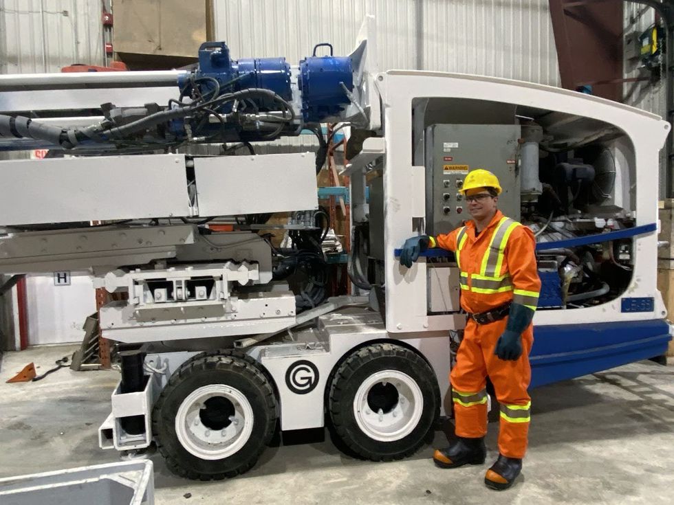 Une personne portant des v\u00eatements de protection haute visibilit\u00e9 se tient devant de lourdes machines.
