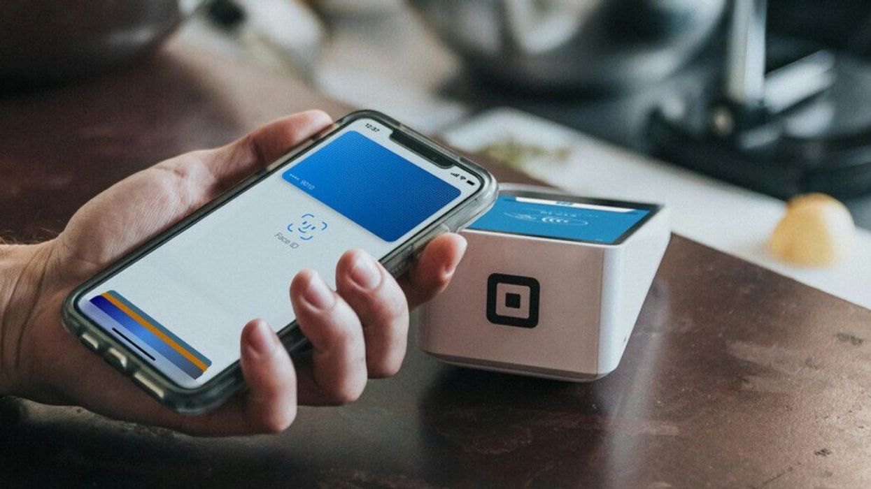 Une personne qui paie à un terminal de paiement avec un téléphone.
