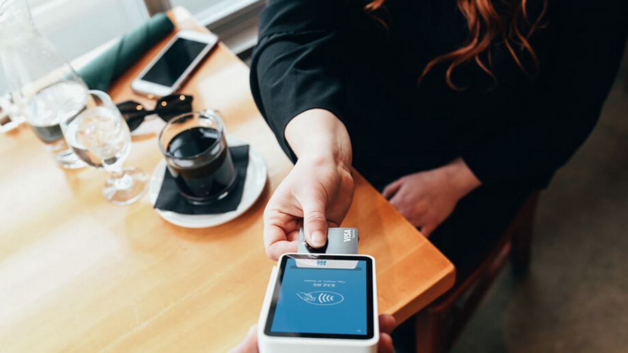 Une personne qui payent à un terminal de banque dans un resto-bar.