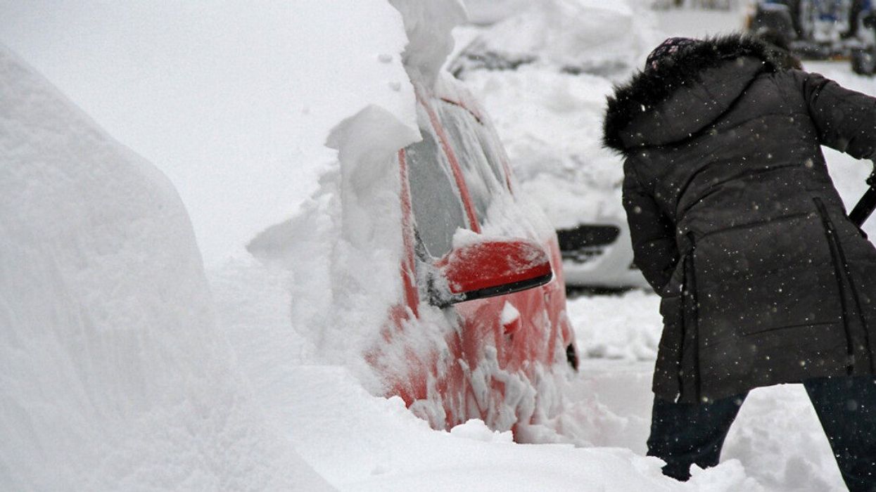 Une personne qui pellette pour enlever la neige de sa voiture.