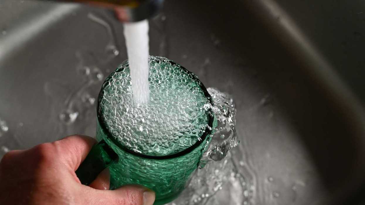 Une personne qui remplit un verre d'eau du robinet.