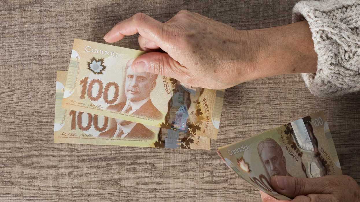 Une personne qui tend des billet de 100 $ canadiens.