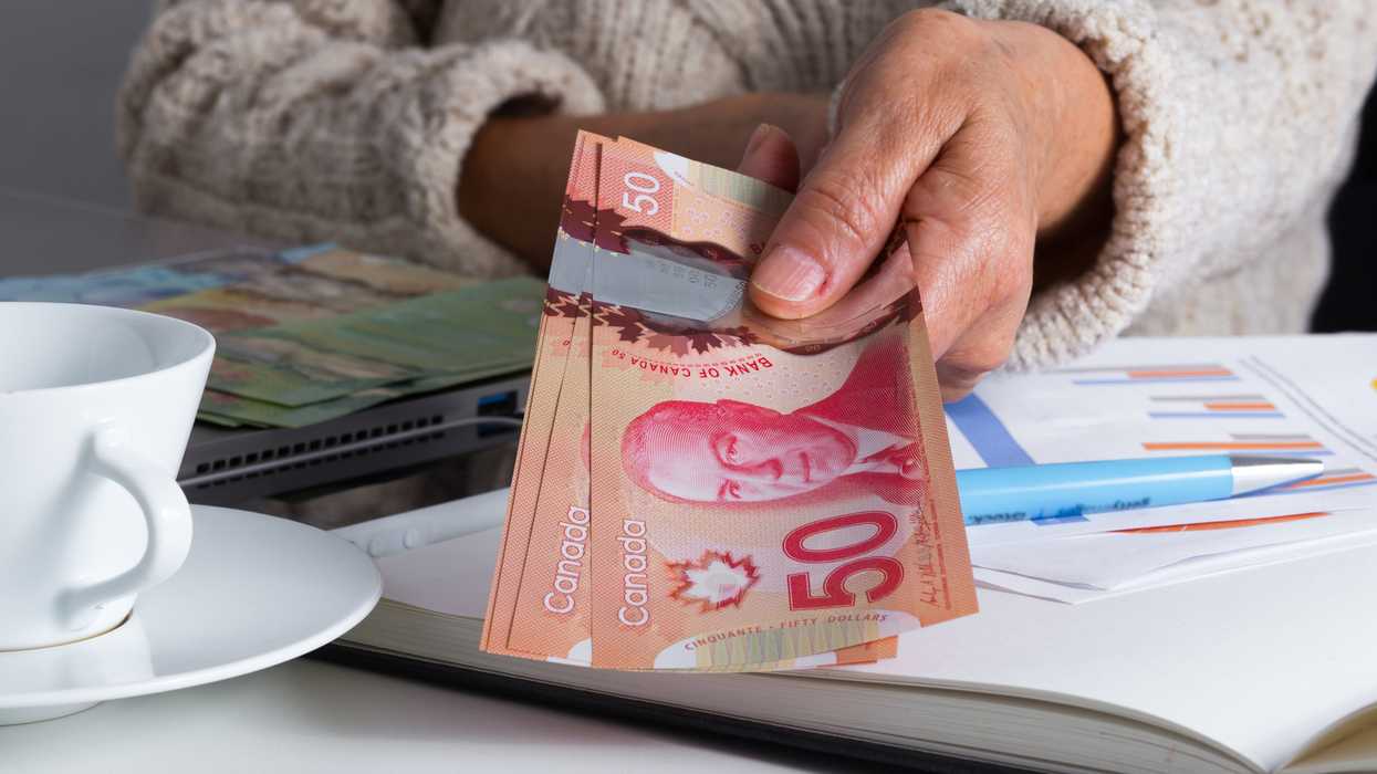 Une personne qui tient des billets d'argent canadien.