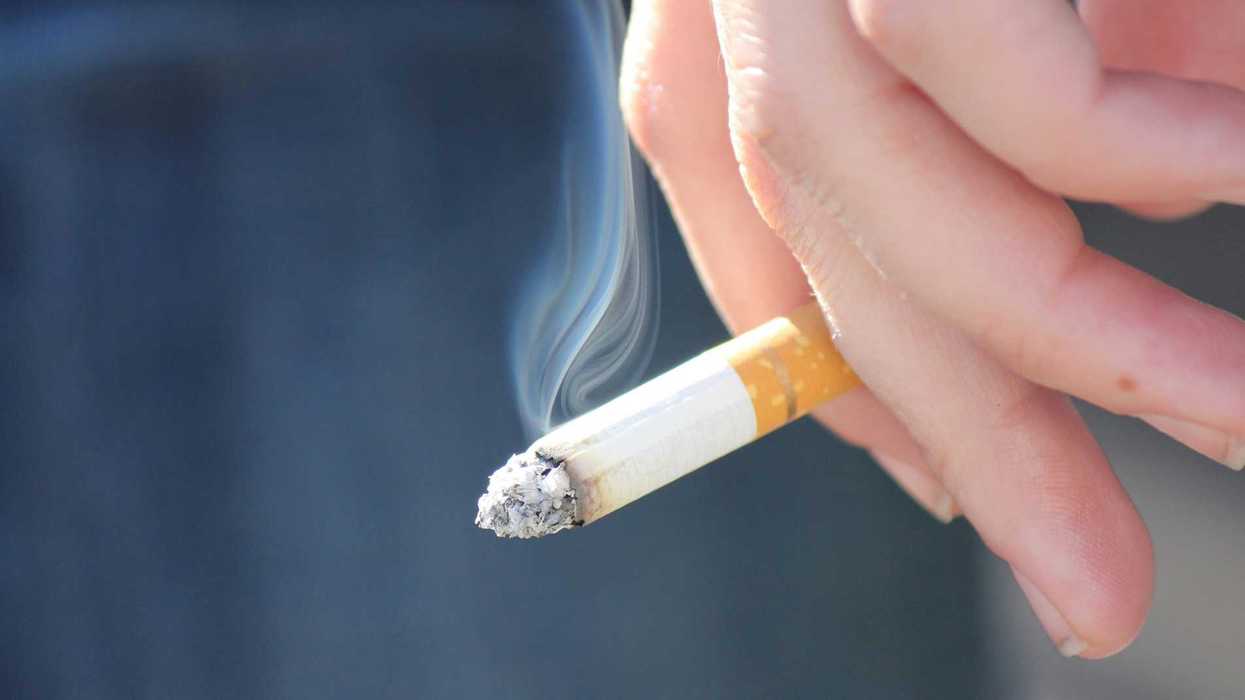 Une personne qui tient une cigarette dans sa main.