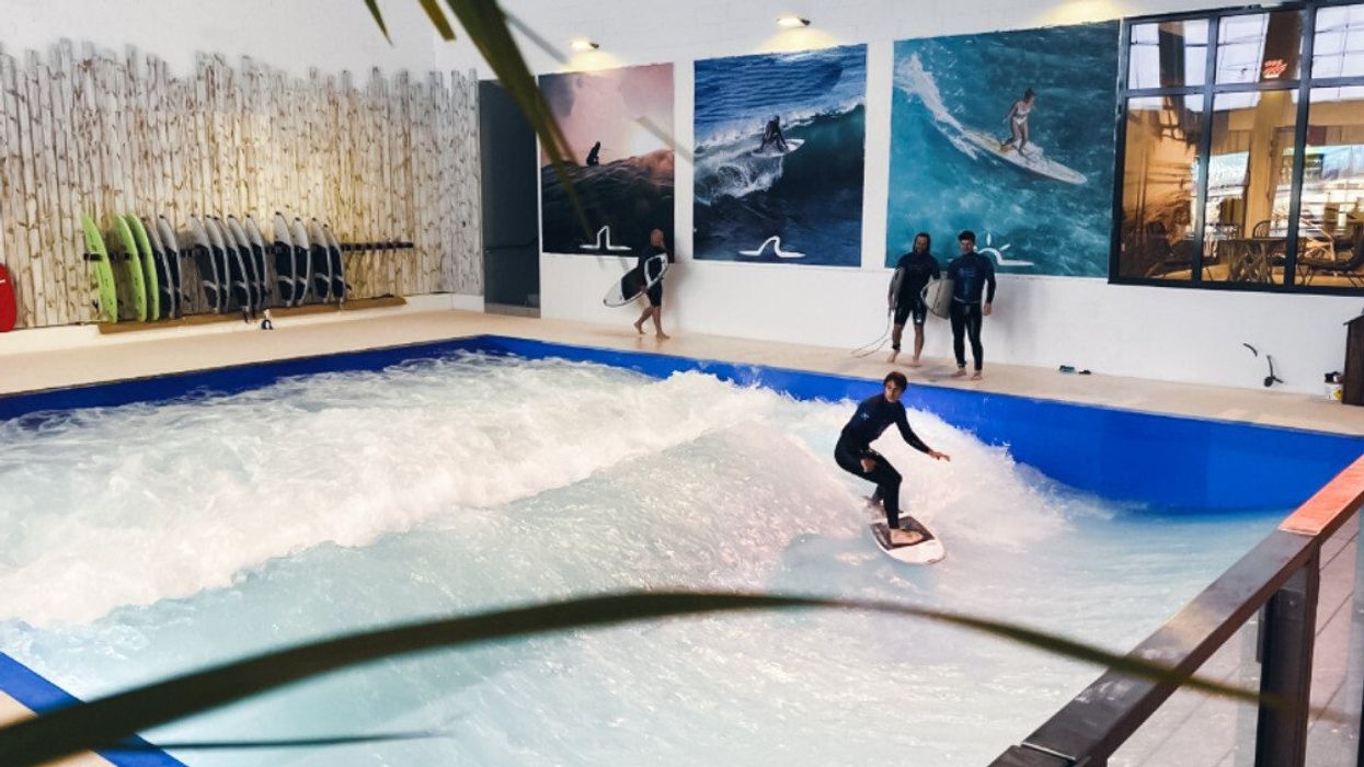 Une personne surfe sur une vague artificielle dans un complexe sportif.