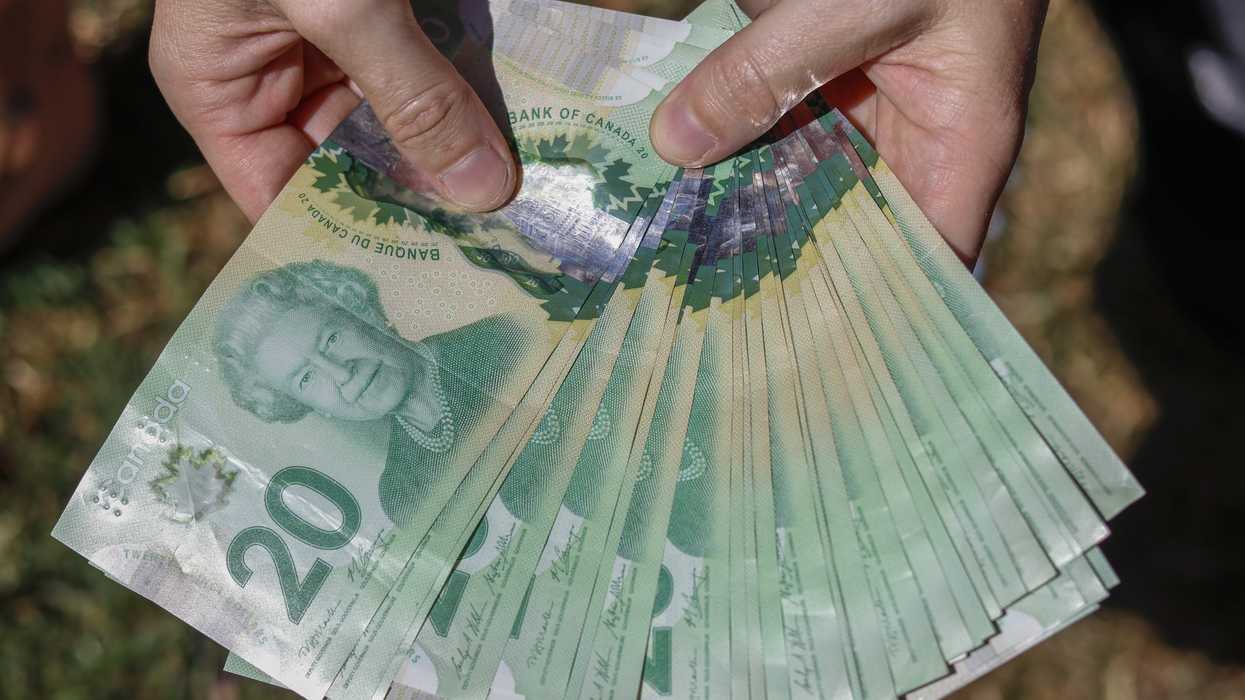 Une personne tenant des billets canadiens.