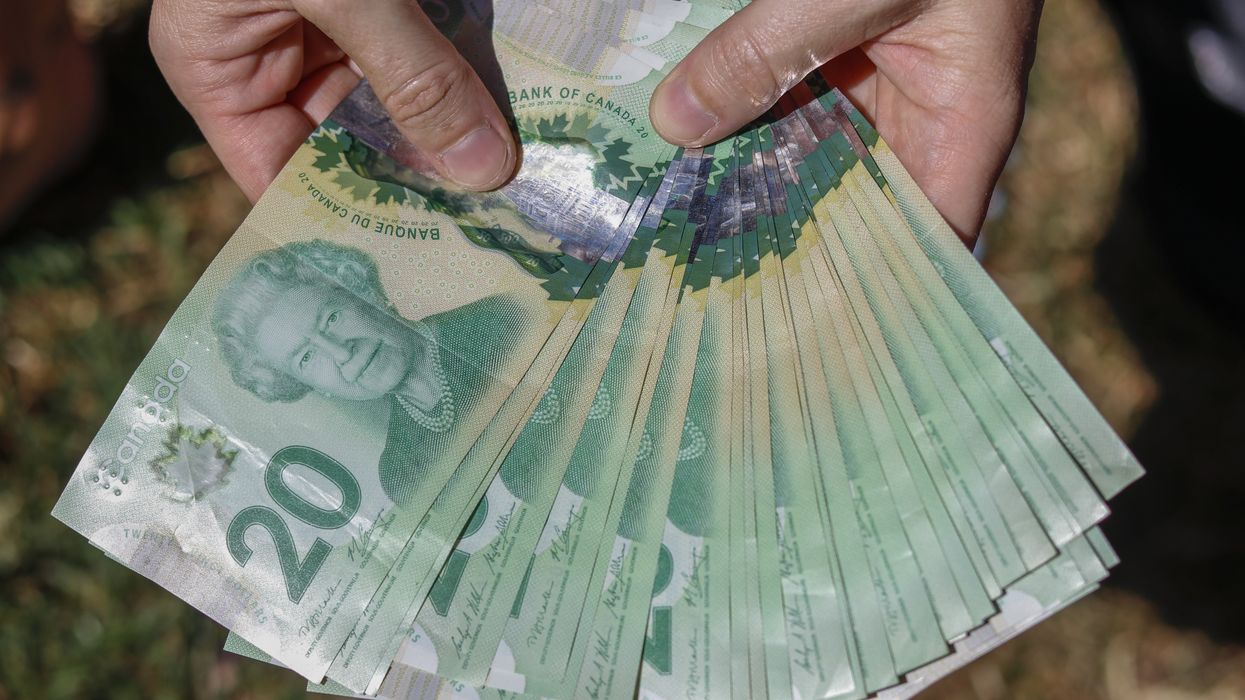 Une personne tenant des billets canadiens.