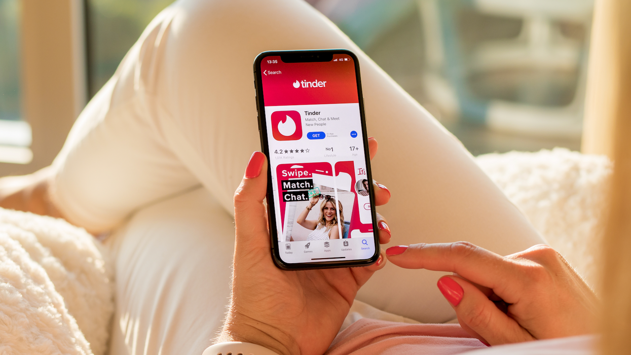 Une personne tenant son cellulaire, ouvert sur la page d'achat de l'application Tinder.