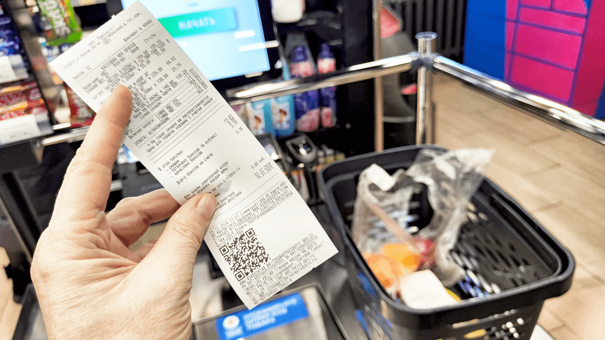 Une personne tenant une facture devant ses achats d'épicerie.