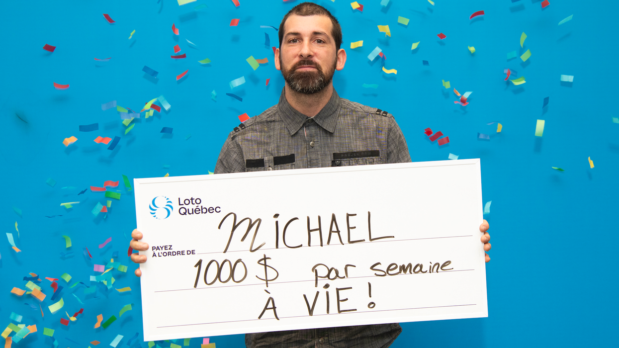 Une personne tient un chèque de 1000 $ par semaine à vie devant un fond bleu.