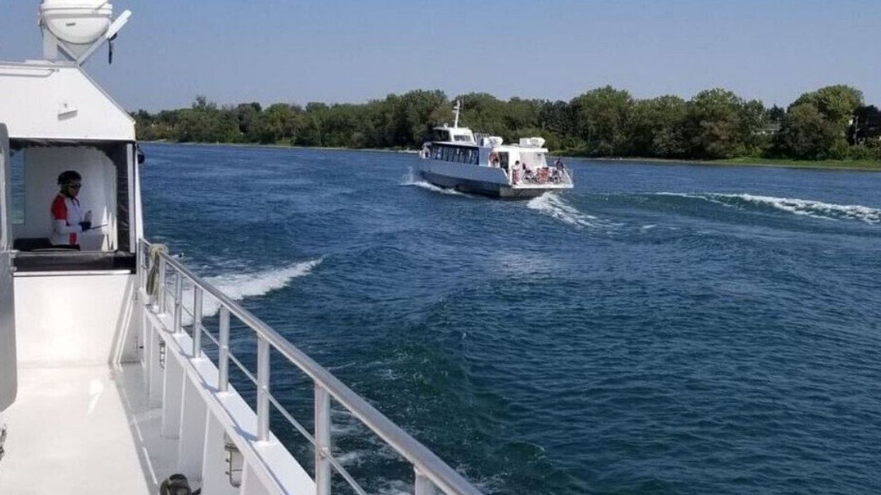 Une photo d'un bateau blanc au loin sur le fleuve Saint-Laurent est prise depuis un autre bateau blanc.