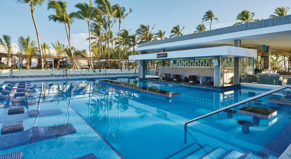 Une piscine avec chaises longues et bar int\u00e9gr\u00e9s \u00e0 l'h\u00f4tel Riu Bambu en R\u00e9publique dominicaine.