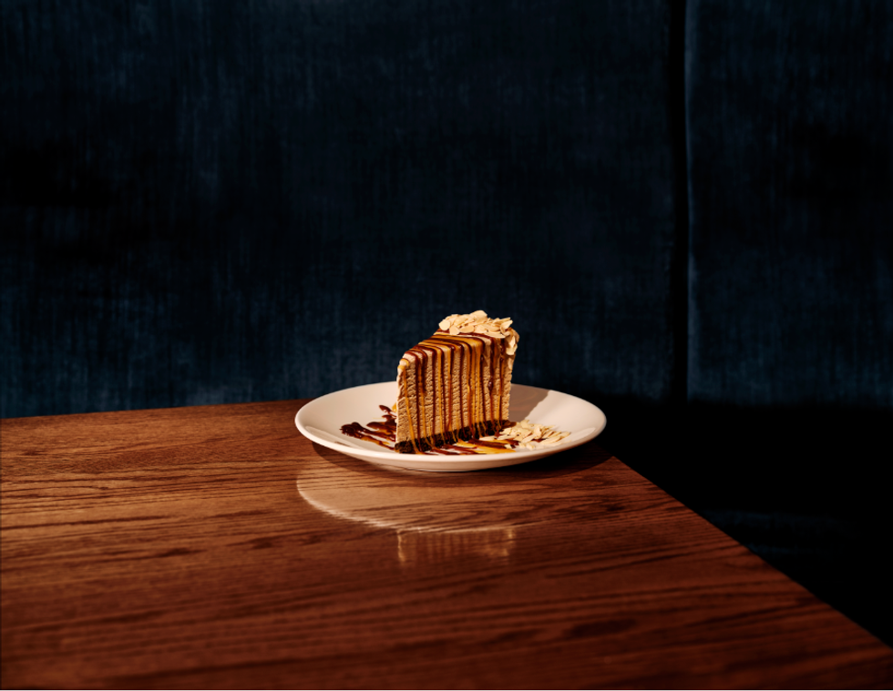 Une pointe d'un g\u00e2teau mousse beige recouvert d'un coulis au chocolat.