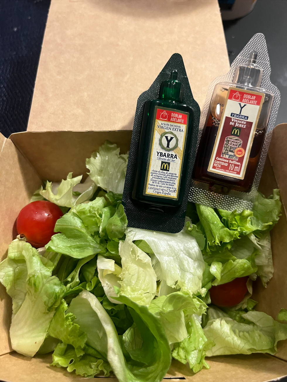 Une salade verte avec un petit pot d'huile d'olive, et un de vinaigre balsamique.