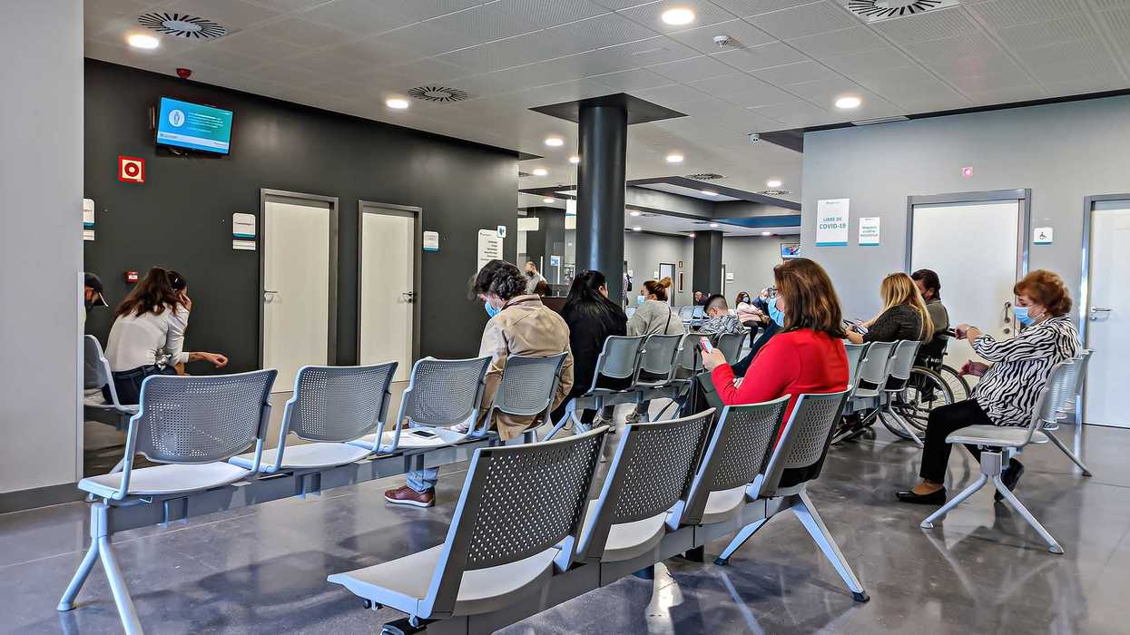 Une salle d'attente d'une clinique avec des gens qui portent un masque.