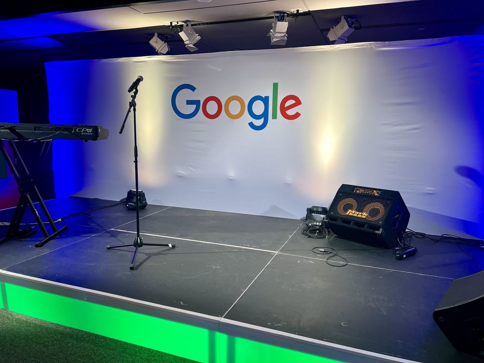 Une sc\u00e8ne illumin\u00e9e avec un tr\u00e9pied et des \u00e9quipements de musique avec un fond blanc o\u00f9 il est inscrit Google.