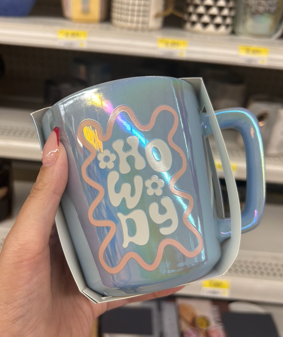 Une tasse \u00e0 caf\u00e9 irridescent bleue et rose avec le mot \u00ab Howdy \u00bb au Walmart.