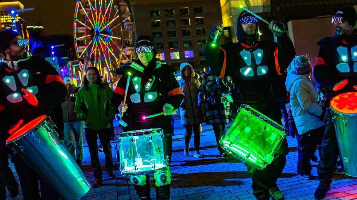 Une troupe de musique avec des tambours illuminés marchant sans le Quartier des spectacles.