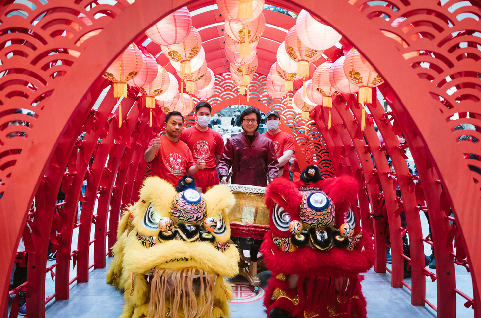 Une troupe musicale avec des marionnettes de lions sous une arche de souhaits pour le Nouvel An lunaire.