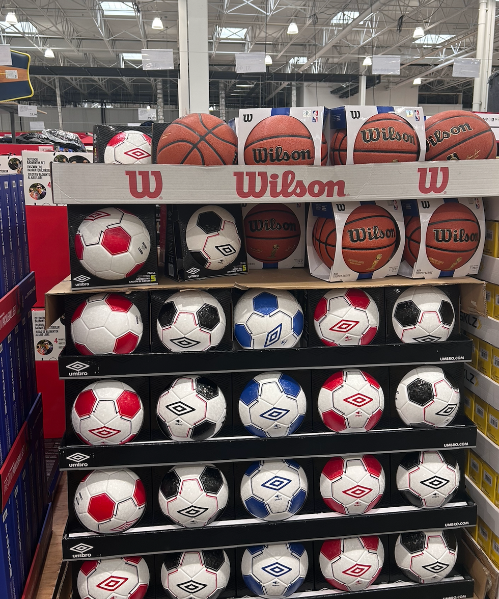 Une \u00e9tag\u00e8re pleine de ballons de basketball et de soccer au Costco.