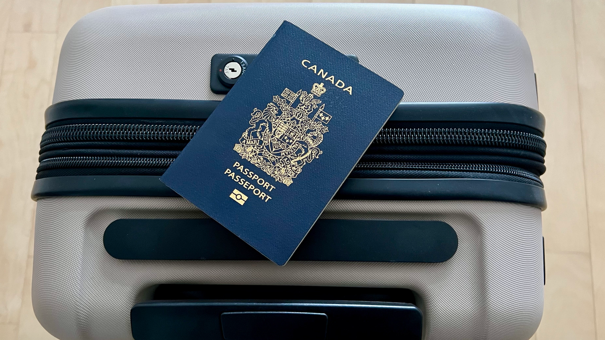 Une valise beige avec un passeport canadien placé sur le dessus.