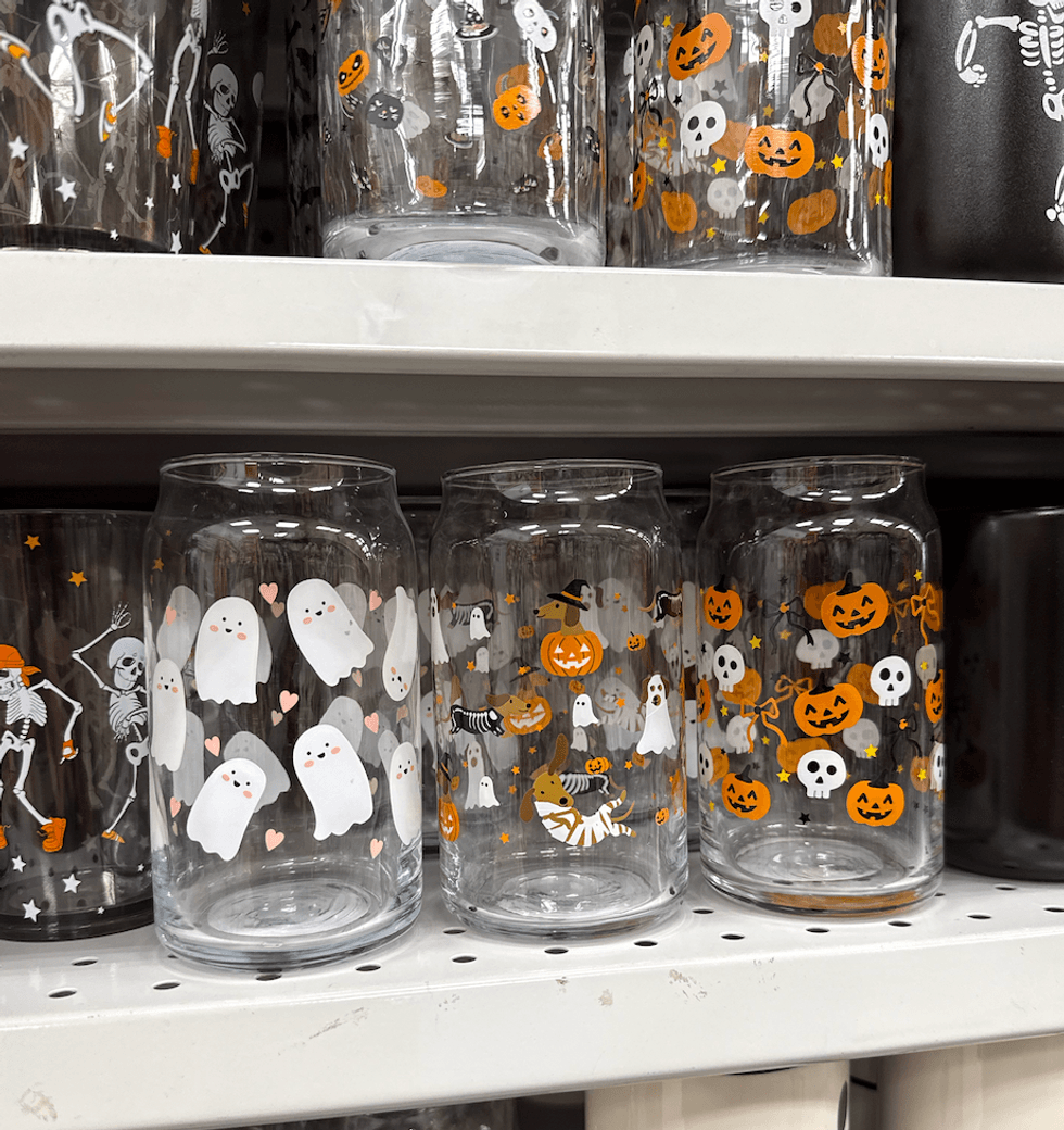 Verres transparents d\u00e9cor\u00e9s de fant\u00f4mes, de citrouilles et de squelettes pour l\u2019Halloween sur une tablette du Dollarama.