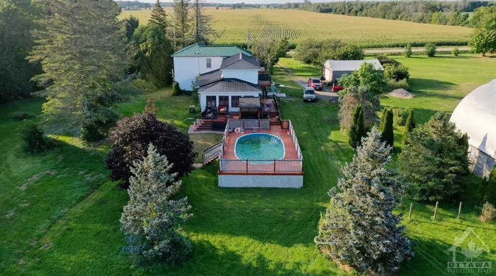 View of the pool, the house, and the field behind it.