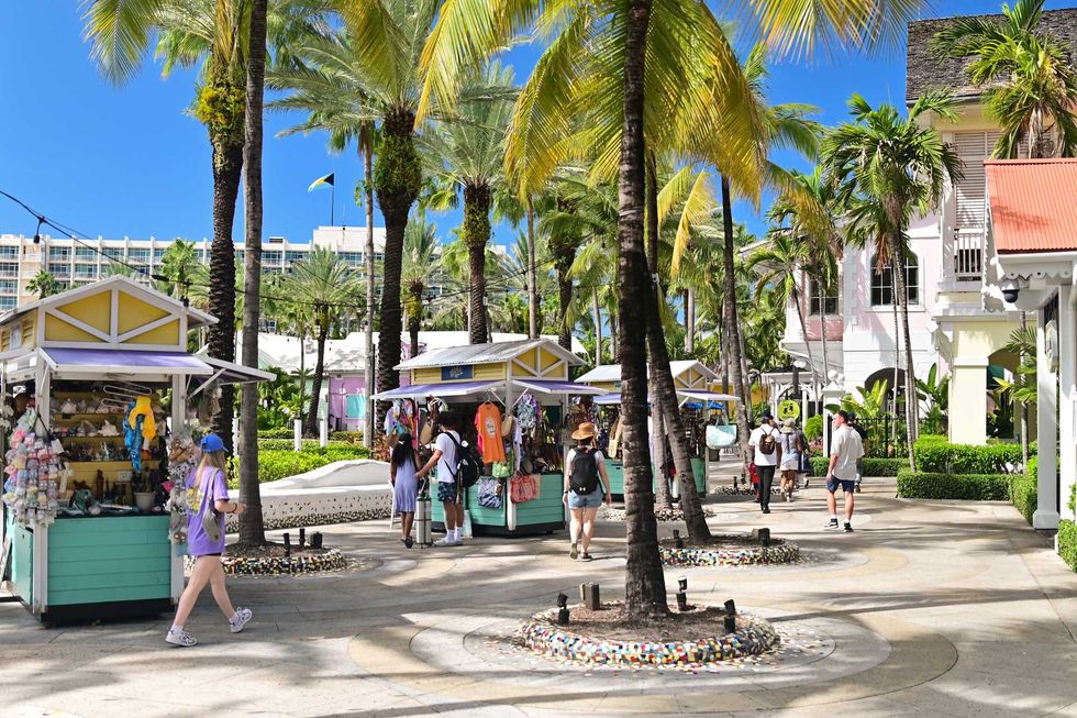 Visitors stroll past vendor booths and palm trees in Nassau's Straw Market in the Bahamas.