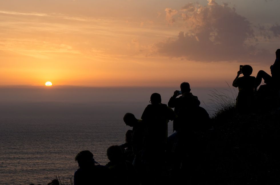 Visitors to Cabo Finisterre watch the spectacular sunset.