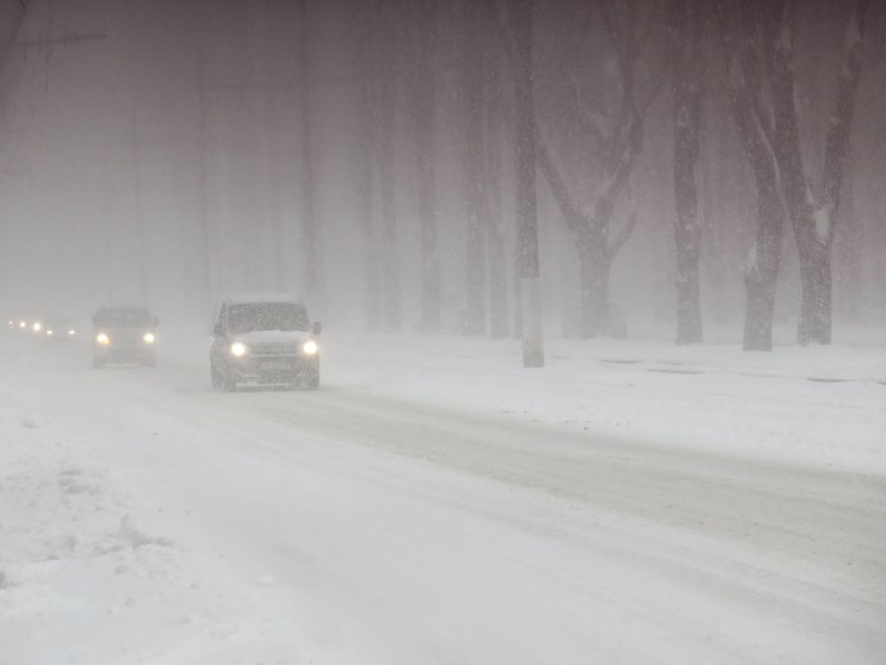 Voitures roulant sur une route enneig\u00e9e avec du brouillard.